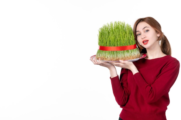 Vista frontal mujer joven sosteniendo gran semeni novruz sobre fondo blanco etnia familia ejecutante vacaciones de primavera concepto étnico