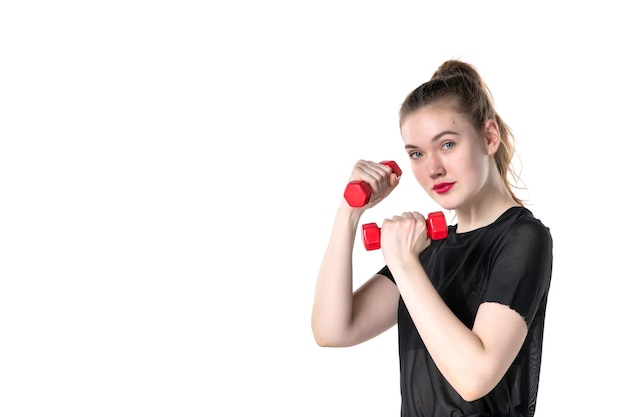 Vista frontal mujer joven trabajando con pesas sobre fondo blanco circo yoga cuerpo salud atleta gimnasio deporte estilo de vida