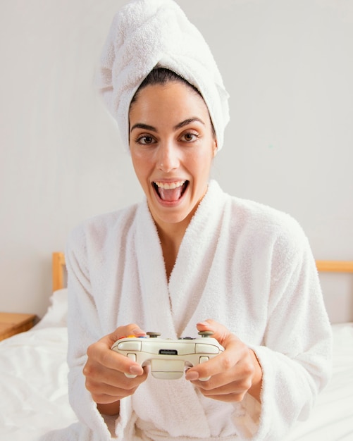 Foto vista frontal de la mujer jugando videojuegos en casa después del baño