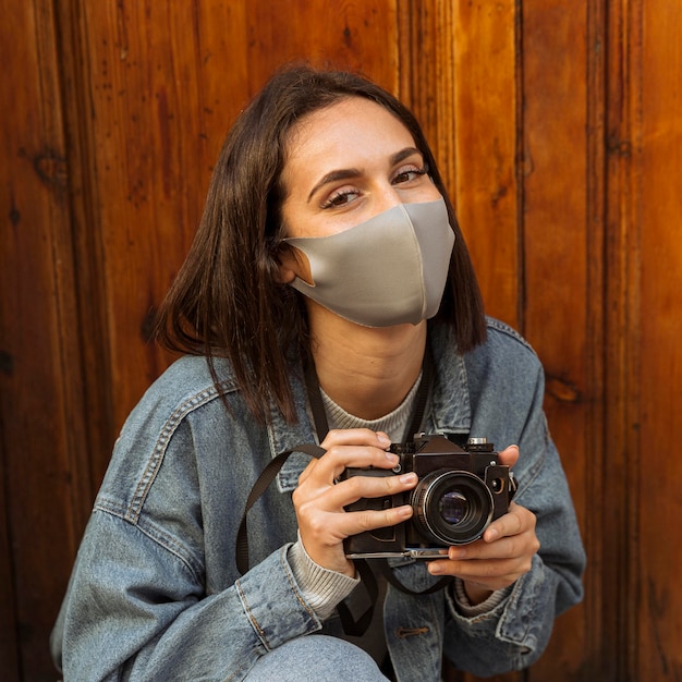 Foto vista frontal, de, mujer, con, mascarilla, tenencia, cámara