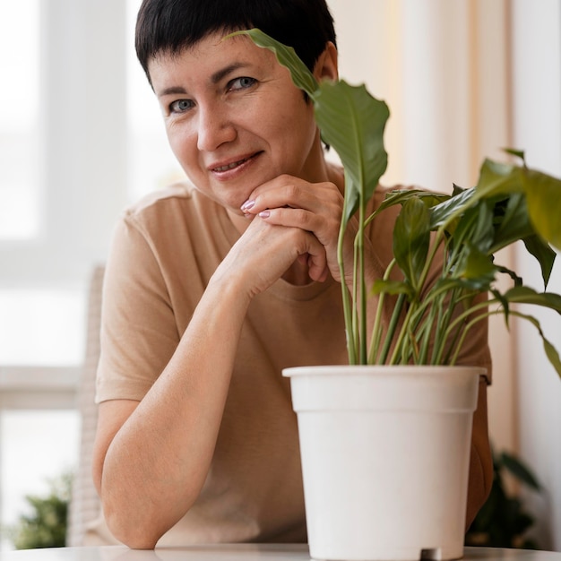 Foto vista frontal de la mujer posando junto a la planta de interior