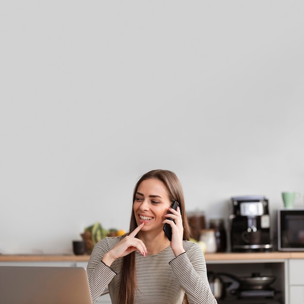 Foto vista frontal mujer sentada en el sofá y habla por teléfono