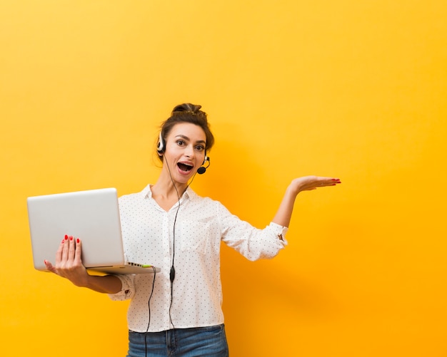 Foto vista frontal de la mujer sonriente con auriculares y sosteniendo portátil