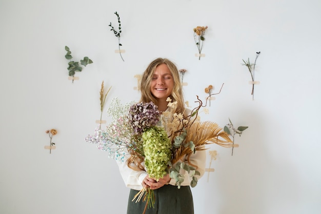 Foto vista frontal de mujer sonriente sosteniendo flores secas