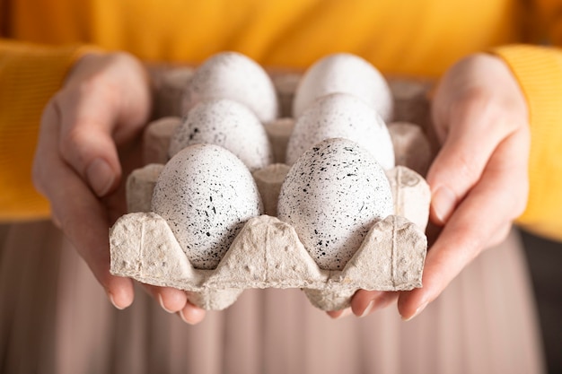 Vista frontal de la mujer sosteniendo huevos de pascua en cartón