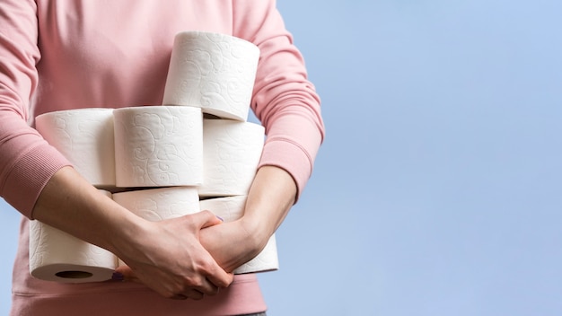 Vista frontal de la mujer sosteniendo muchos rollos de papel higiénico con espacio de copia