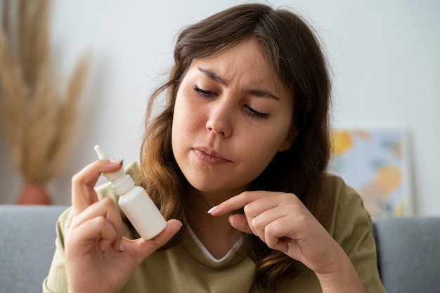 Vista frontal mujer sosteniendo spray nasal