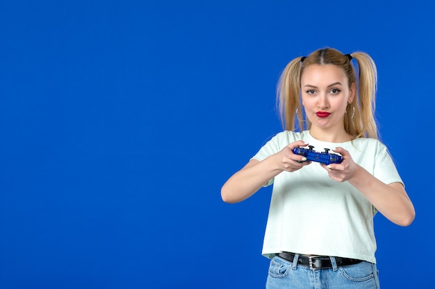 Foto vista frontal de las mujeres jóvenes con gamepad sobre fondo azul adulto alegre jugador virtual internet ganador de video en línea sofá juvenil horizontal