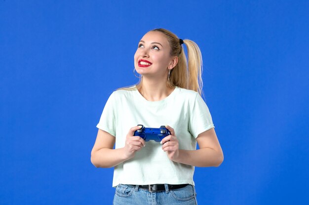 Vista frontal de las mujeres jóvenes con gamepad sobre fondo azul en línea jugador de alegría virtual juvenil alegre ganador de video joystick adultos