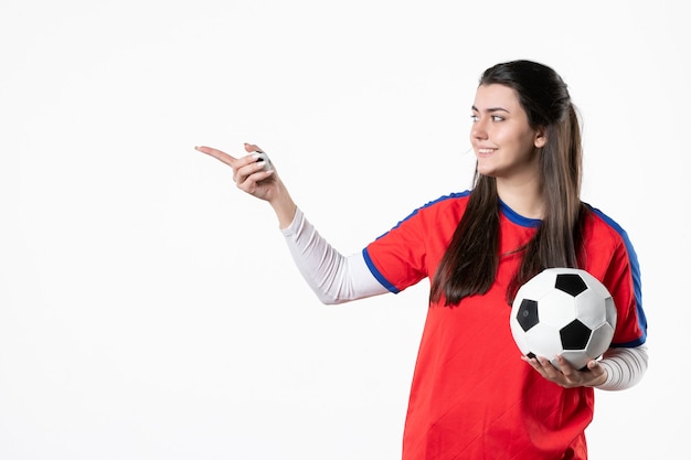 Vista frontal de las mujeres jóvenes en ropa deportiva con balón de fútbol en la pared blanca