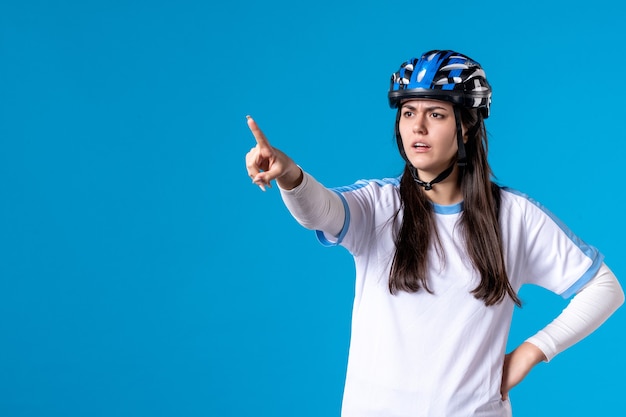 Vista frontal de las mujeres jóvenes en ropa deportiva con casco en la pared azul