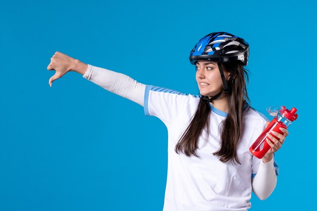 Vista frontal de las mujeres jóvenes en ropa deportiva con casco en la pared azul