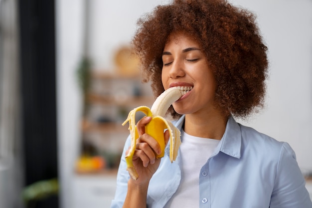 Foto vista frontal mulher comendo banana