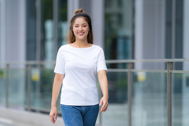 Vista frontal, Mulher de camiseta branca e calça jeans, do lado de fora na rua da cidade, dia de verão