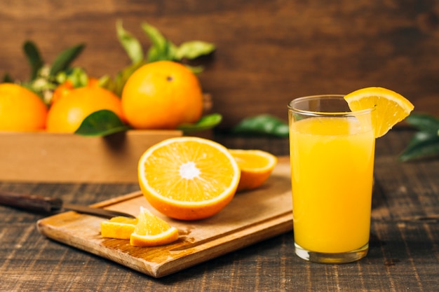 Foto vista frontal naranja a la mitad junto a jugo de naranja