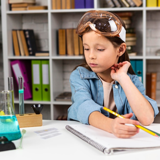 Foto vista frontal de la niña con gafas de seguridad haciendo experimentos científicos