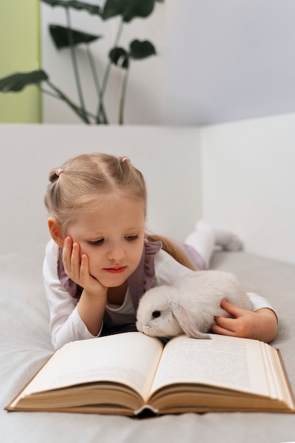 Vista frontal niña leyendo con conejito