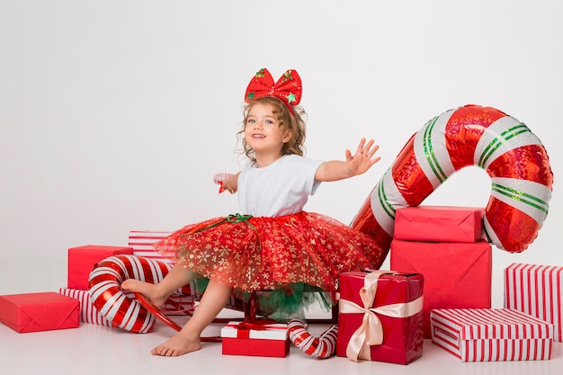 Foto vista frontal niña rodeada de elementos navideños