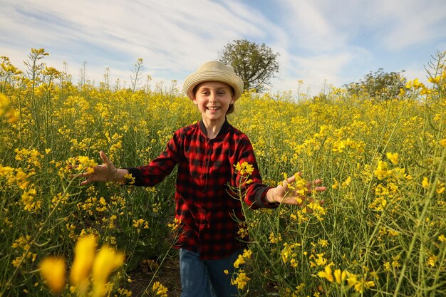 Vista frontal de un niño alegre niños con sombrero corriendo con los brazos extendidos en un día soleado encantador