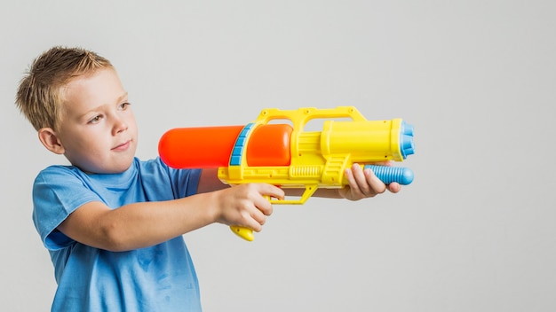 Foto vista frontal niño lindo con pistola de agua