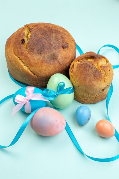 vista frontal ovos de páscoa coloridos com deliciosos bolos na superfície azul ornamentado feriado páscoa colorido multi cores primavera