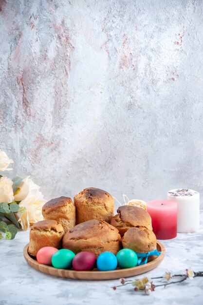 vista frontal ovos de páscoa coloridos com pão e bolos de férias dentro da bandeja no fundo branco conceito de torta primavera doces ornamentados coloridos