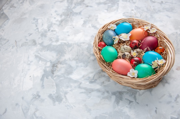vista frontal ovos de páscoa coloridos dentro da cesta na superfície branca primavera páscoa conceito colorido feriado ornamentado
