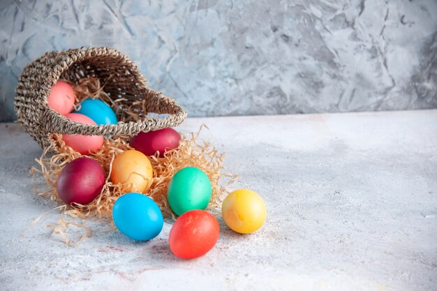 vista frontal ovos de páscoa coloridos dentro de uma bela cesta na superfície branca