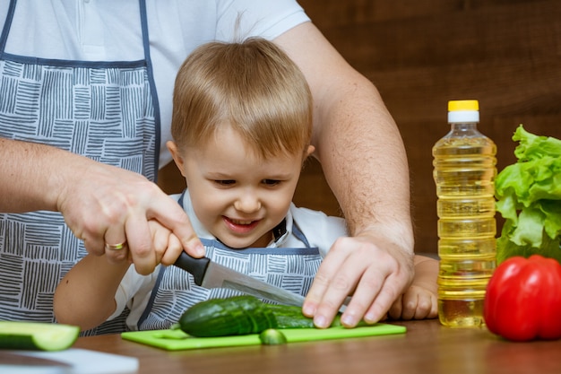 Vista frontal pai e filho na cozinha cortar legumes para salada