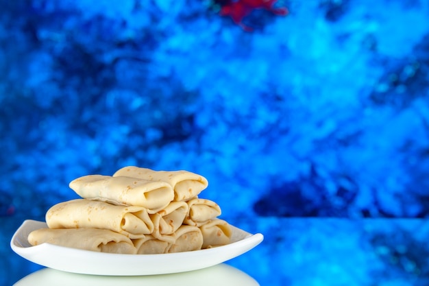 Vista frontal de panqueques dulces enrollados dentro de la placa sobre fondo azul comida de la mañana desayuno pastel color azúcar comida leche