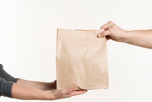 Foto vista frontal de un par de manos sosteniendo una bolsa de papel