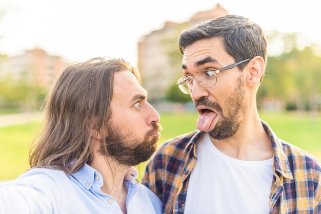 Vista frontal de una pareja gay divertida mirándose y haciendo muecas en el parque