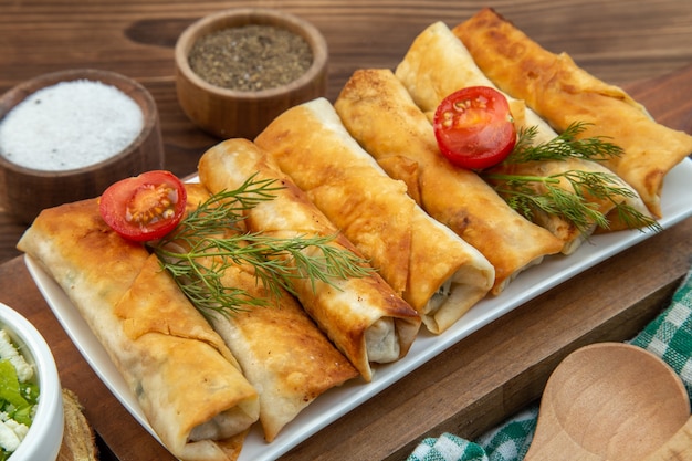 Vista frontal de pasteles verdes fritos con tomates rojos sobre el fondo marrón cocinar comida tarta cena pastelería carne