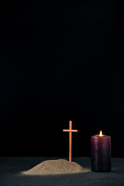 Vista frontal de la pequeña tumba con vela encendida en negro