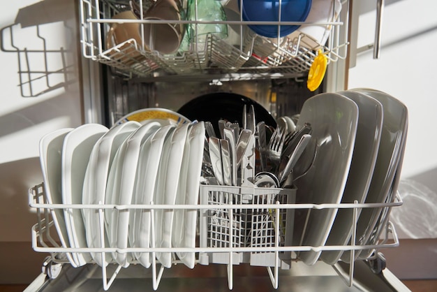 Vista frontal de platos y utensilios en un lavavajillas.