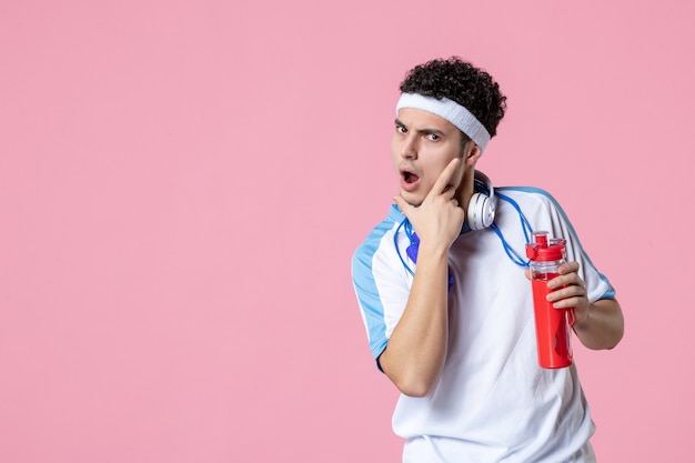 Vista frontal posando de atleta masculino em roupas esportivas com garrafa de água