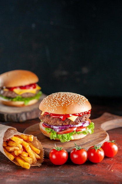Vista frontal saboroso hambúrguer de carne com batatas fritas em fundo escuro jantar hambúrguer lanche fast-food sanduíche salada prato torrada