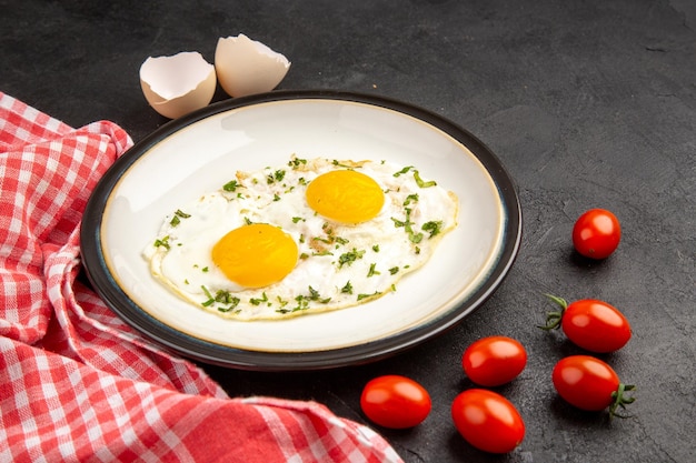 Vista frontal sabrosos huevos revueltos con tomates rojos sobre fondo oscuro tortilla de pan comida desayuno almuerzo té comida mañana