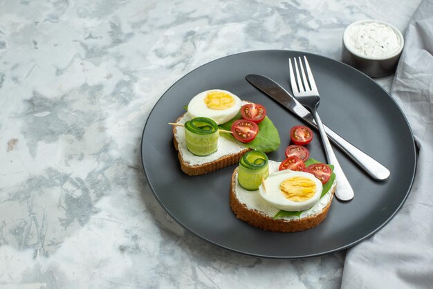 Vista frontal sabrosos sándwiches de huevo con cuchillo y tenedor placa interior fondo blanco sándwich dieta tostada comida salud hamburguesa pan comida almuerzo