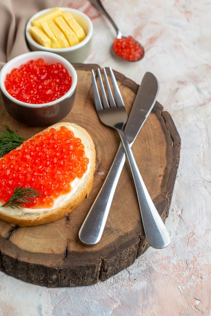 Vista frontal sanduíches de caviar com talheres e queijo na tábua de corte em superfície clara