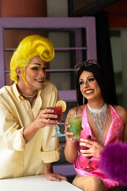 Foto vista frontal smiley drag queens con bebidas