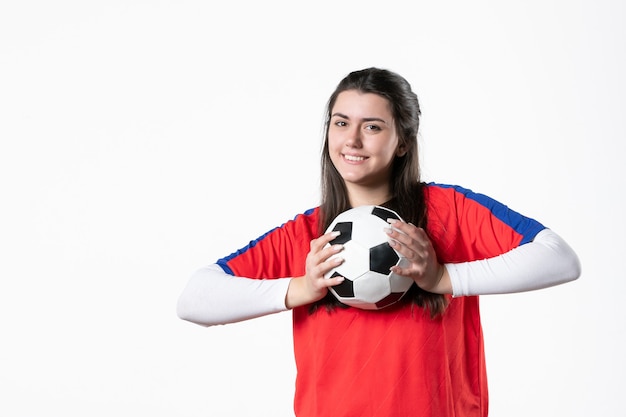 Vista frontal sonriente mujer joven en ropa deportiva con balón de fútbol