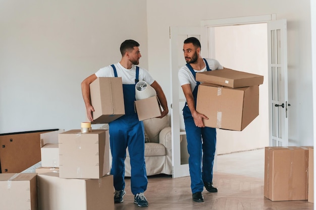 Vista frontal sosteniendo cosas dos empleados de servicio en movimiento en una habitación