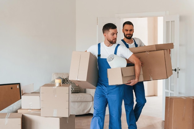 Vista frontal sosteniendo cosas dos empleados de servicio en movimiento en una habitación
