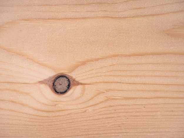 Foto vista frontal de una tabla de madera con dibujos del grano formando ondas y un gran nudo en forma de ojo con sus anillos de crecimiento