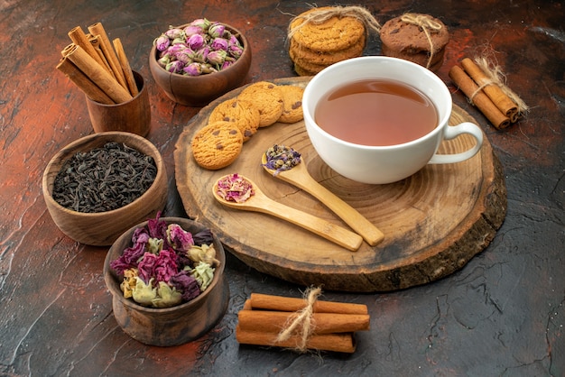 Vista frontal taza de té con galletas y flores sobre fondo oscuro sabor flor color té café foto