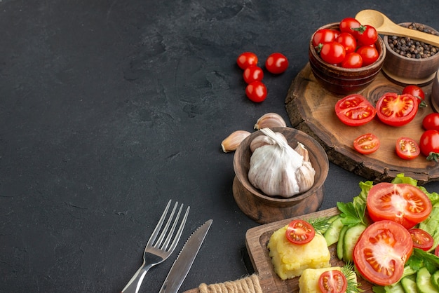 Vista frontal de todo el corte de verduras frescas y especias sobre tabla de madera cubiertos de toalla blanca juego de queso sobre superficie negra