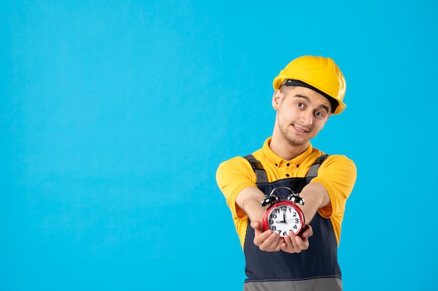 Vista frontal del trabajador de sexo masculino en uniforme amarillo dando relojes en azul