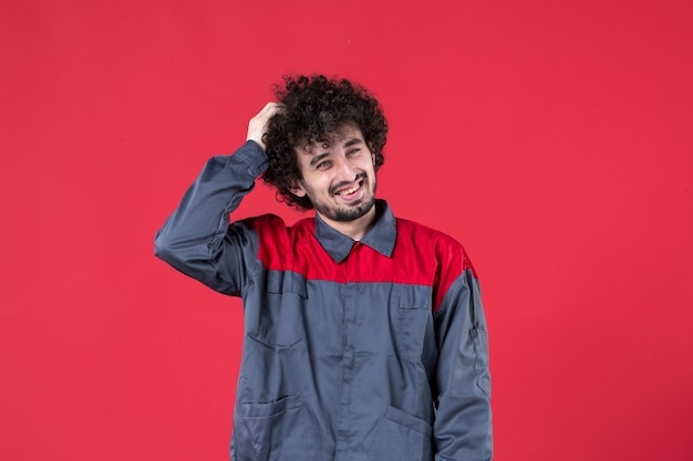 Vista frontal trabajador de sexo masculino en uniforme sobre fondo rojo mecánico foto casa color trabajo trabajador herramienta instrumento