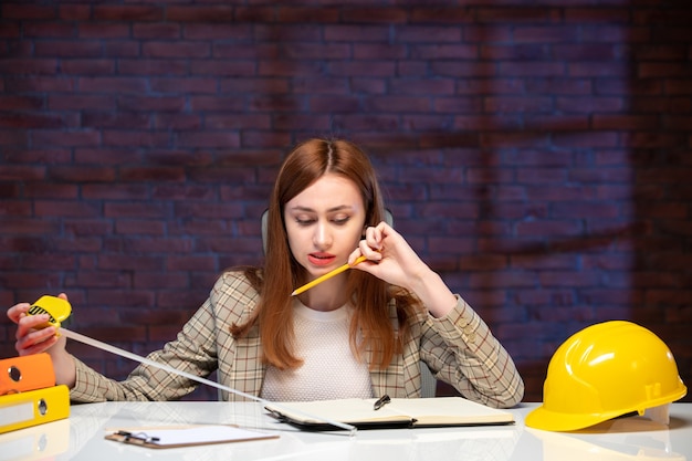 vista frontal trabalhadora no canteiro de obras segurando fita métrica e escrevendo notas agenda projeto corporativo gerente de plano de trabalho de negócios